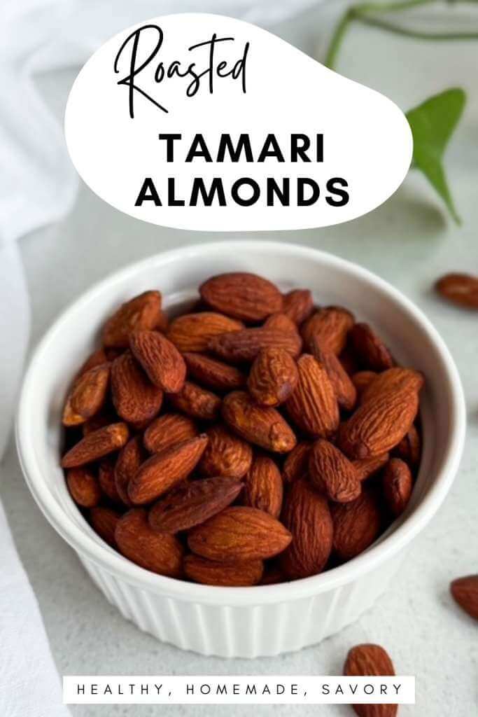 A white bowl filled with glossy roasted tamari almonds on a light background with a few almonds scattered nearby, topped with text that reads “Roasted Tamari Almonds” and a small banner saying “Healthy, Homemade, Savory.”