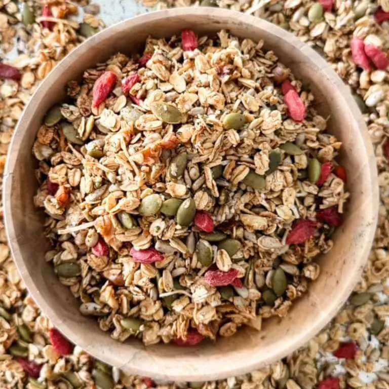Bowl of homemade granola with oats, pumpkin seeds, sunflower seeds, walnuts, coconut, and dried berries.