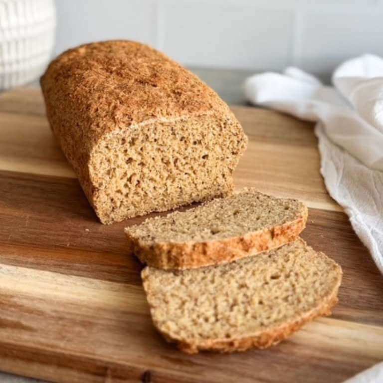 Sliced oatmeal flax bread on a wooden cutting board with a soft, slightly dense texture