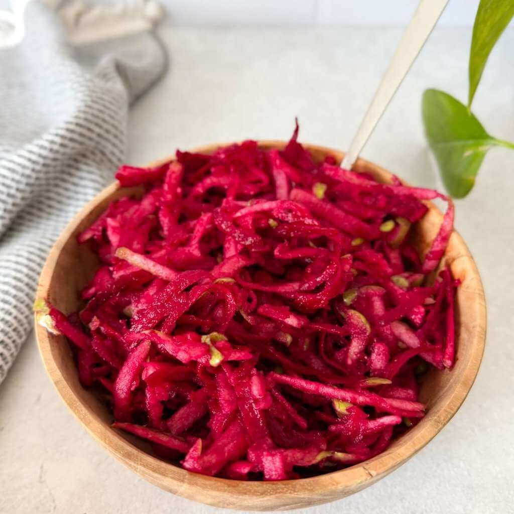 Beet and apple salad in a wooden bowl with a spoon