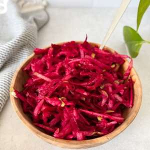Beet and apple salad in a wooden bowl with a spoon