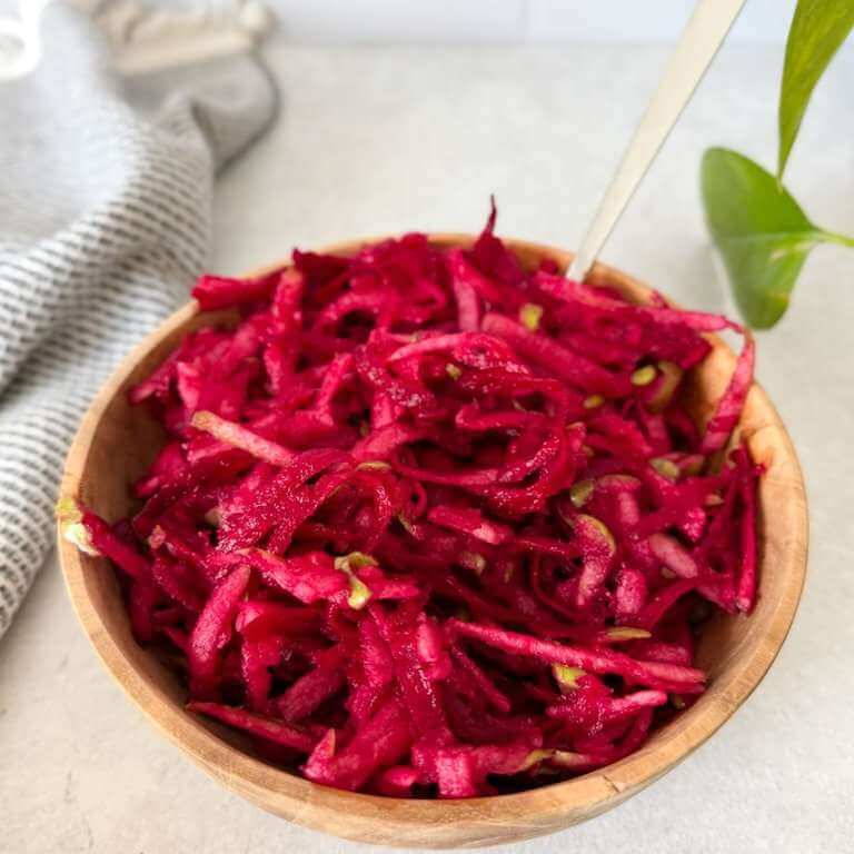 Beet and apple salad in a wooden bowl with a spoon