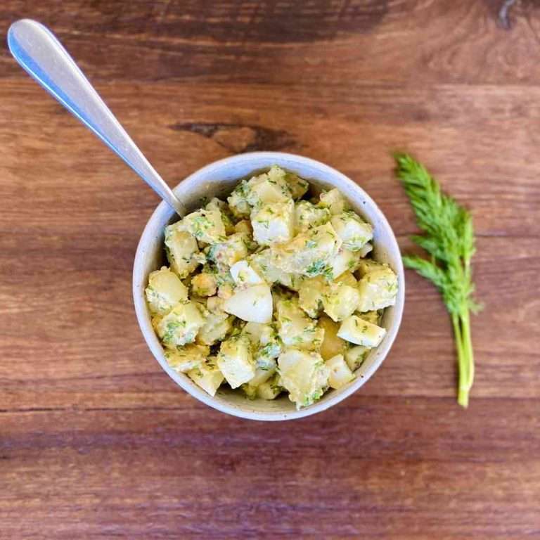 low fodmap potato salad in a bowl with a spoon on a wood backdrop