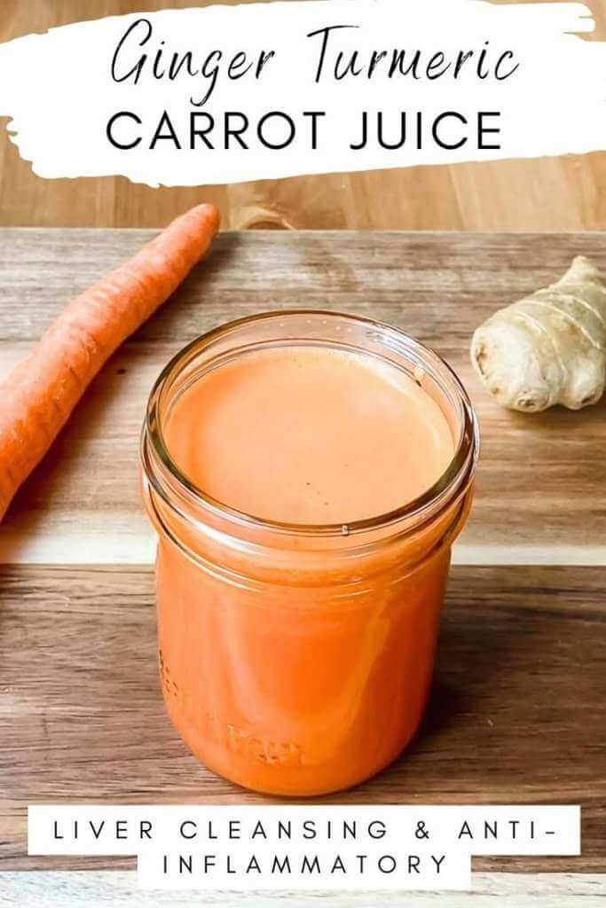 Turmeric Ginger Carrot Juice in a mason jar on a wood table with a whole carrot and knob of ginger on the side