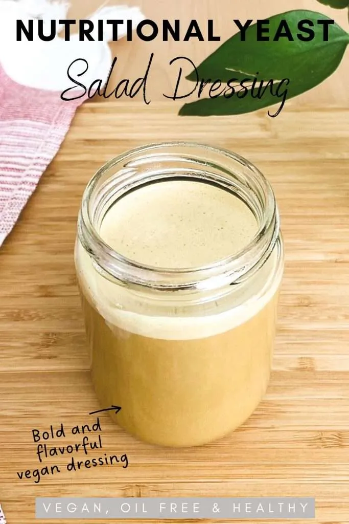 Nutritional yeast salad dressing in a glass jar on a bamboo chopping board.