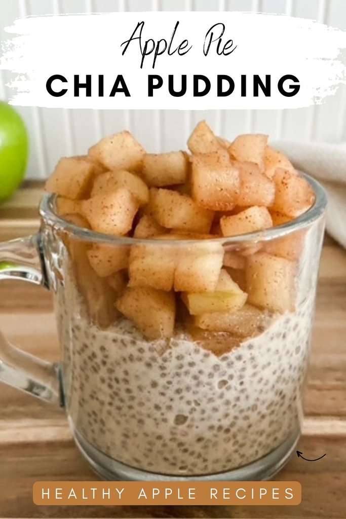 Glass mug filled with creamy apple pie chia pudding topped with cinnamon-spiced apples on a wooden surface, with a green apple in the background.