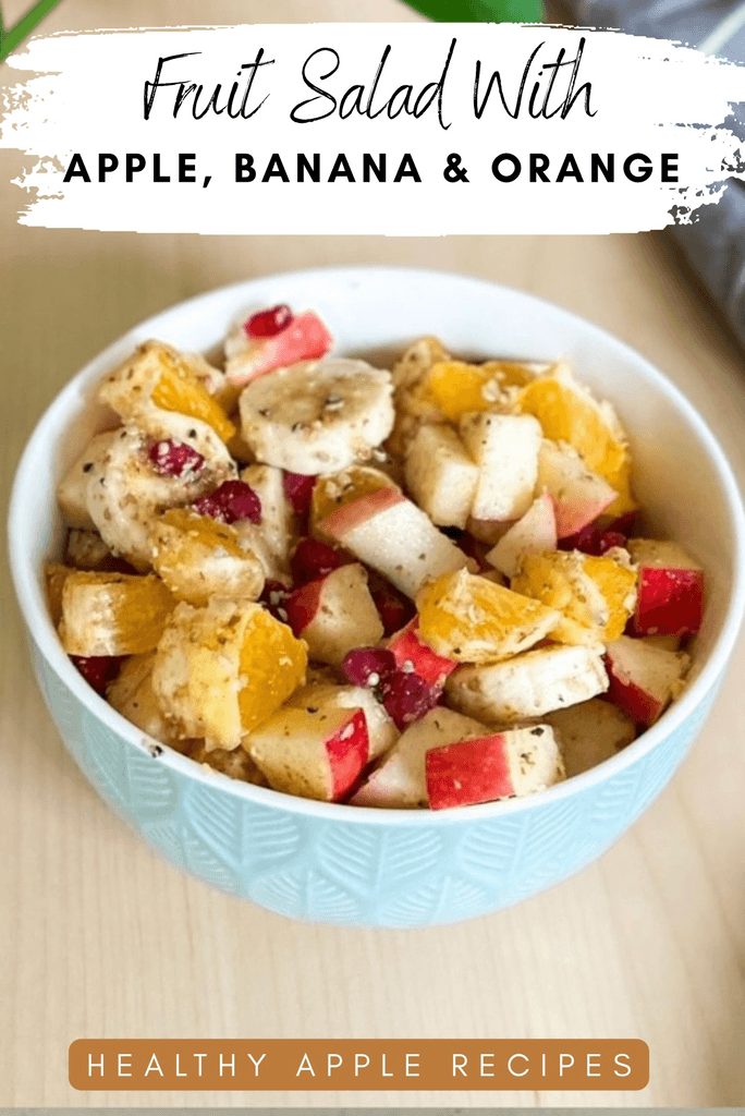 Fruit salad in a blue bowl on a wood table with orange, apple and banana and text overlay that says "fruit salad with apple, banana & orange" and "healthy apple recipes"
